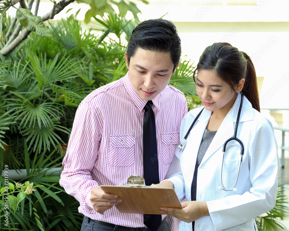 Wall mural south east asian young malay chinese man woman medical doctor talking discussing outdoor