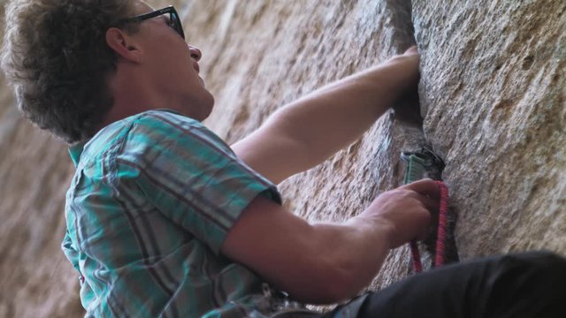 Low angle view of rock climber clipping into wall lock protection