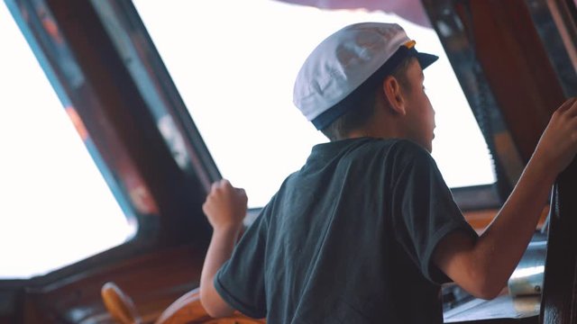 A Young Boy At The Steering Wheel  Of A Boat In Marmari Village, Kos Island, Greece - close up