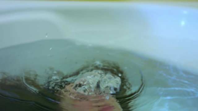 The young woman was submerged under water. I dive in the bathtub. Exhales. Oxygen bubbles escape from her nose. She is drowning. Danger in the bathtub.