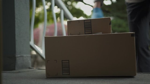 Daylight exterior close up of entrance to house front porch, as box delivery is placed into frame. 4K.