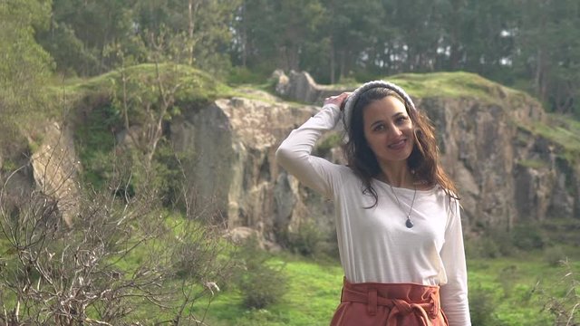 Woman spinning around and taking off her wool cap in a forest, slow motion