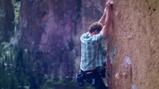 Young climber in vertical Smith Rock arete clipping rope in carabiner