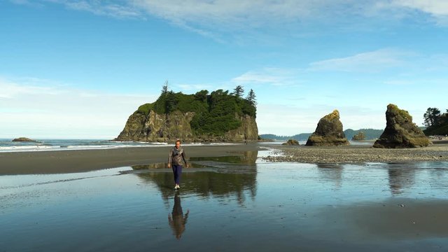 Woman Walks Away from Giant Rocks on Ruby Beach in Olympic National Park, Washington in Summer