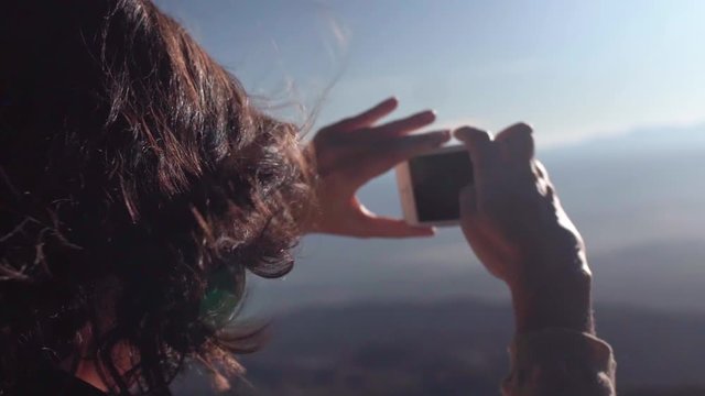 Woman taking photo of a sunset with an iPhone