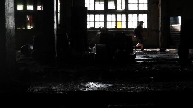 abandoned factory, dripping water from the roof, dark technical room with a beautiful light from the window. In the background, in the blurry background, a silhouette of a man is visible
