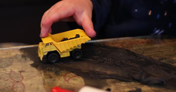A close-up of a child's hands playing with his tow digger and clay inside during lockdown