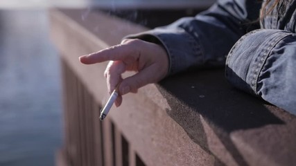 Tired, homeless woman flicks the ashes on her cigarette. Part of a series in slow motion where she smokes.