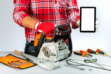 Repair of chainsaws,gasoline powered tools. Repairman holding digital tablet. Price list. Repair company services.