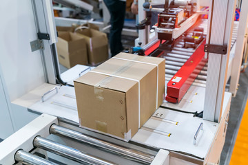 cardboard box of product packaging is moving on conveyor belt of automatic packing machine in the...