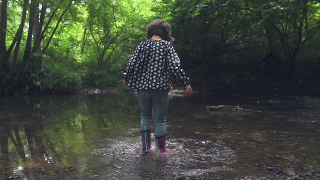 Little girl playing and splashing in the river.