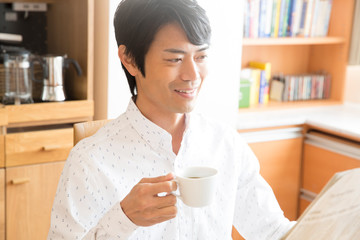 珈琲を飲みながら新聞を読む男性
