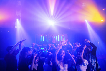 crowd of people raises hands dancing together on dancefloor in nightclub