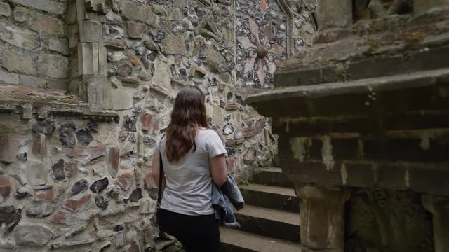 Woman exploring a medieval terrace wall in a park in Norwich, England