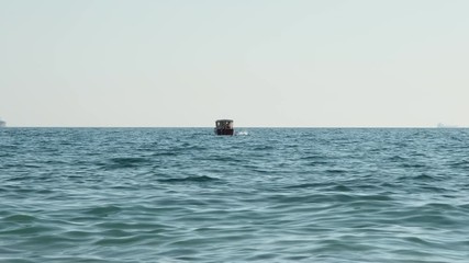 From a distance you can see how unrecognizible girl jumps from yacht into the open sea or ocean. Young people rented boat and hang out on it.