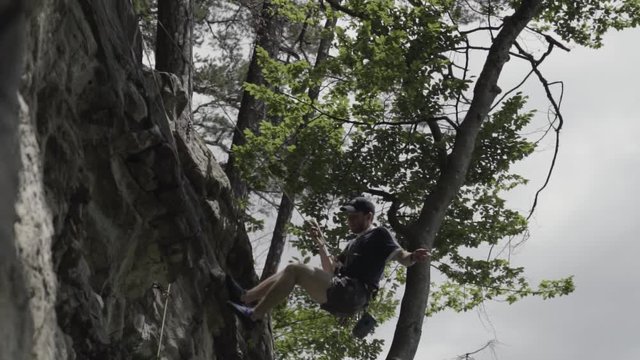 Experienced Male Climber Rappelling Down A Rocky Cliff In Bockstor Near Interlaken, Switzerland - Slow Motion