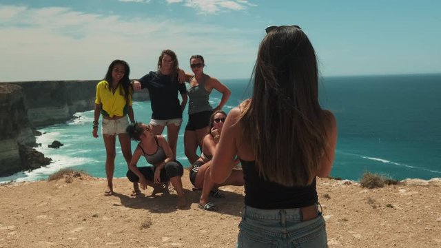 Woman taking photos of girl group on holiday trip in Australia during beautiful weather