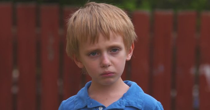 Portrait of a sad little boy turning toward the camera.