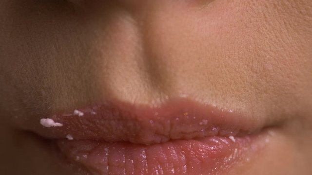 Woman bites zephyr and licks lips twice, static close up.