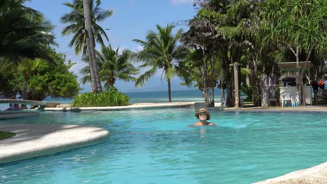 Dos Palmas Island Resort, Puerto Princesa, Palawan, Philippines - Lovely Female Tourist Swimming In A Beautiful Infinity Pool Surrounded With Palm Trees On A Sunny Day - Low-Level Shot