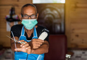 Both hands of the male barber held the clippers and scissors.