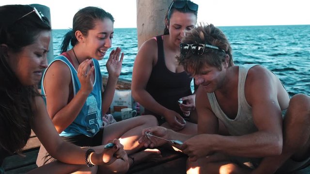 Group of girls learn to prepare a bait for squid fishing. Fisherman teaching  squid fishing to a group of tourists