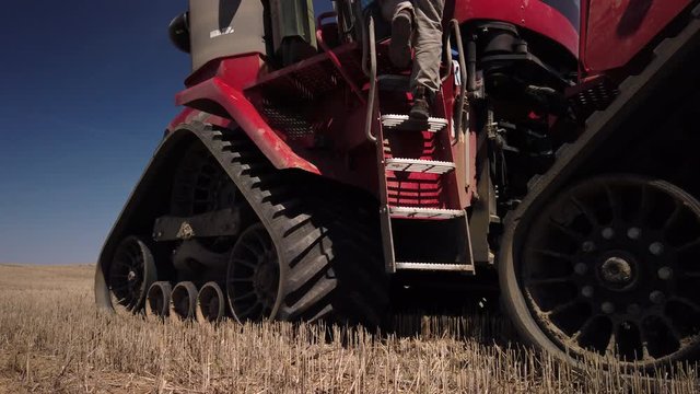 Farmer Getting Into The Track Farm Tractor With Triangular Wheels On The Farm - medium shot