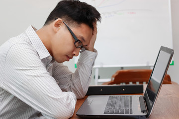 Stressed tired young Asian business man feeling depressed worried about problem in workplace of office. Businessman in panic