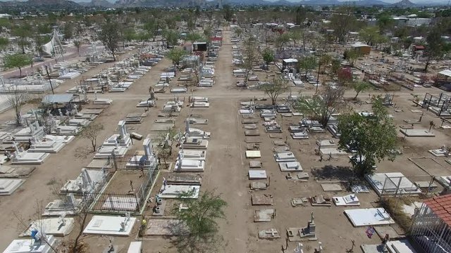 Vista a&eacute;rea sobre las tumbas de un cementerio en una zona desertica. El drone volando al frente.
