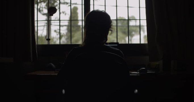4K at 24fps / Woman on the computer on a rainy day with backlight / Mistery mood