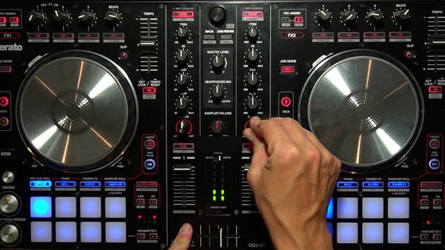 DJ Mixing Music with Digital Controller Turning Knobs overhead Party