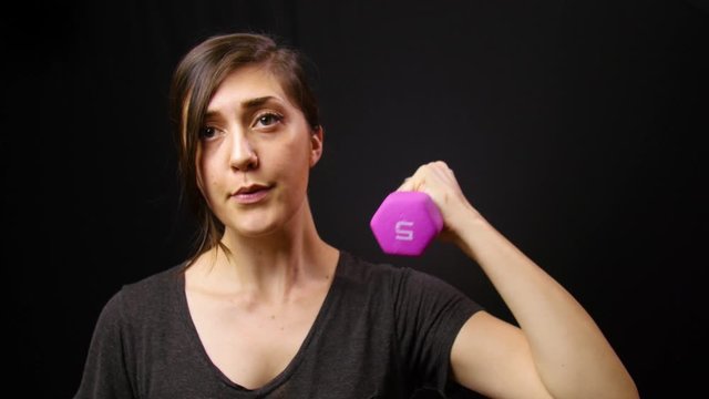 Woman lifts dumbbell weight for her home workout.