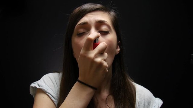 Woman uses inhaler to breathe after having an asthma attack.