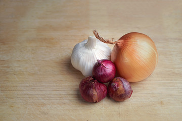 Red Onion, Yellow or Sweet Onion and Garlic on Wooden Cutting or Chopping Board.