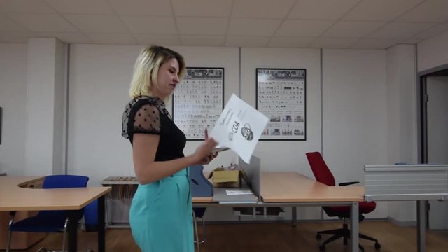 Spanish female worker throwing paperwork while walking through office. Tracking shot