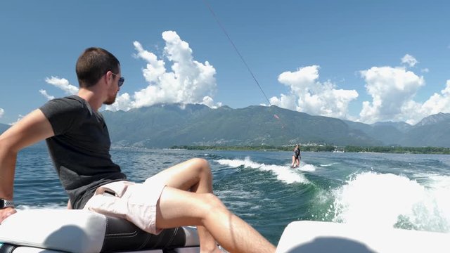 tourist wakeboarding in Lake Maggiore, man watching back of boat on summer holiday 