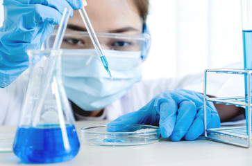 Scientists hold the pipette and drop the blue chemical liquid for research and analysis in a...