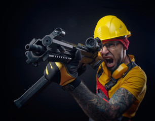 Fototapeta premium a man in a construction worker's uniform wearing a hard hat with an airsoft weapon in his hands