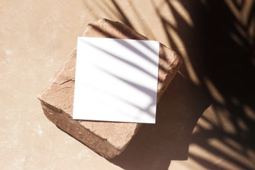Blank paper sheet cards template, stone and sunlight palm shadows on beige textured background. Flat lay, top view.copy space. Business mock up .