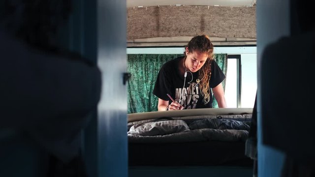 Slow motion shot of concentrate young woman painting image inside bus vehicle