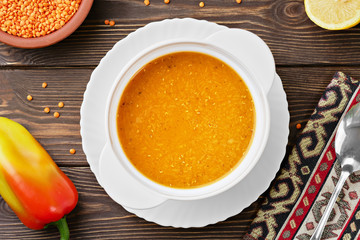 Homemade Turkish lentil soup (Merdzimek Chorbasy). Red lentil soup on a dark wooden table, ingredients for the soup next to a plate. Healthy and wholesome food. Top view, flat lay