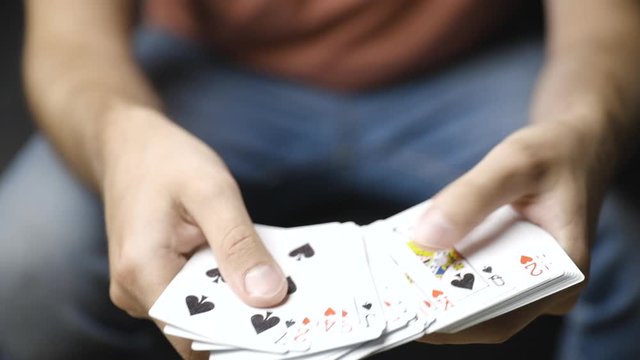 Male hands shuffle playing cards and browse through deck, close-up