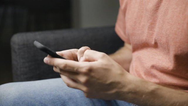 Close view from side of young male hands typing on black smartphone