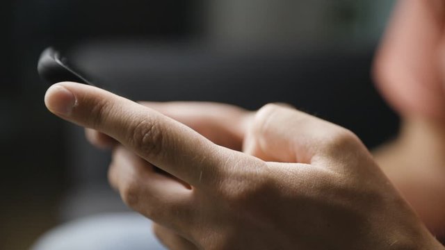 Close-up from side of male hands typing on smartphone, shallow DOF