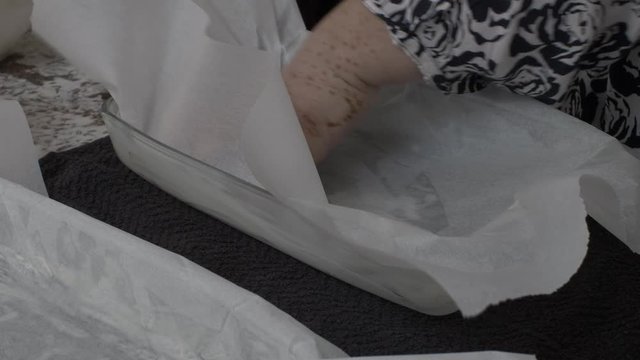 Greaseproof Paper Being Applied To Pyrex Dish By Hand. Locked Off