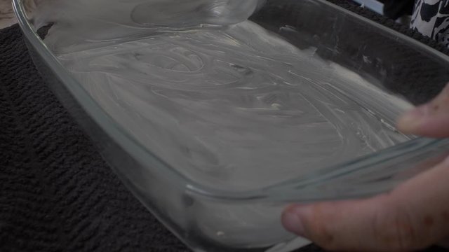Adult Female Greasing Inside Of Pyrex Dish With Butter. Low Angle, Close Up