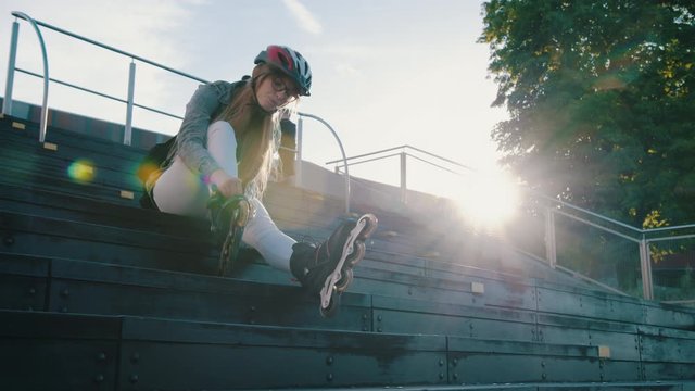 Woman is going rollerblading. Sitting  on the stairs and putting on inline skates. Sport lifestyle