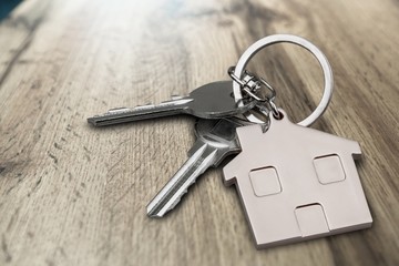 Metal silver house keys with house figure on desk