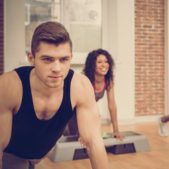 Portrait of three athletic friends training together and doing push-ups with platform