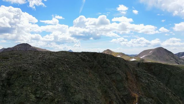 Aerial view 360 degree Shot, A man standing on rocky peak of Mountain in San Juan Mountain Range in Colorado.